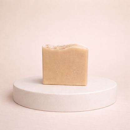 NU-MI beige reinigingszeep voor droge huid gepresenteerd op een minimalistische ronde display.