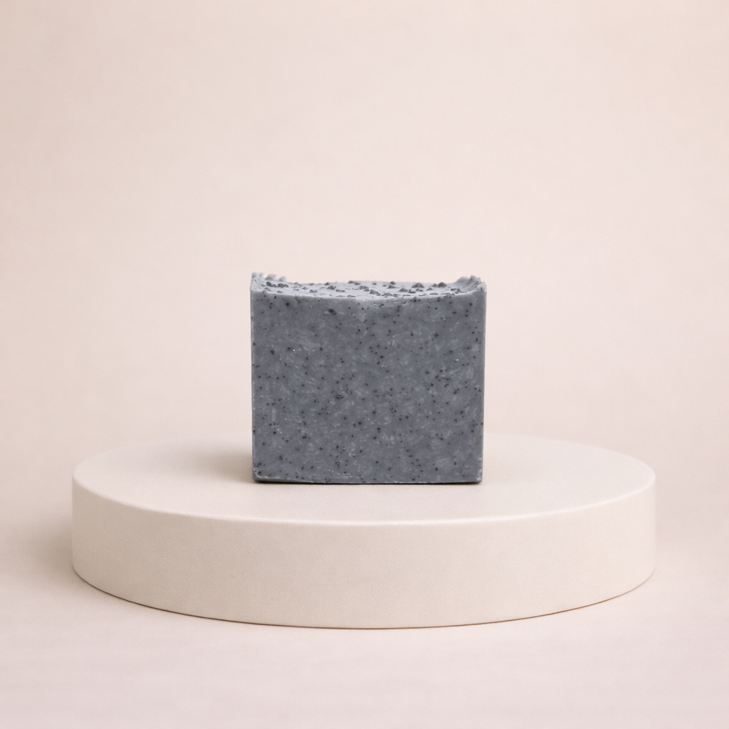 NU-MI exfoliërende scrubzeep voor vette en onzuivere huid op een minimalistische ronde display.